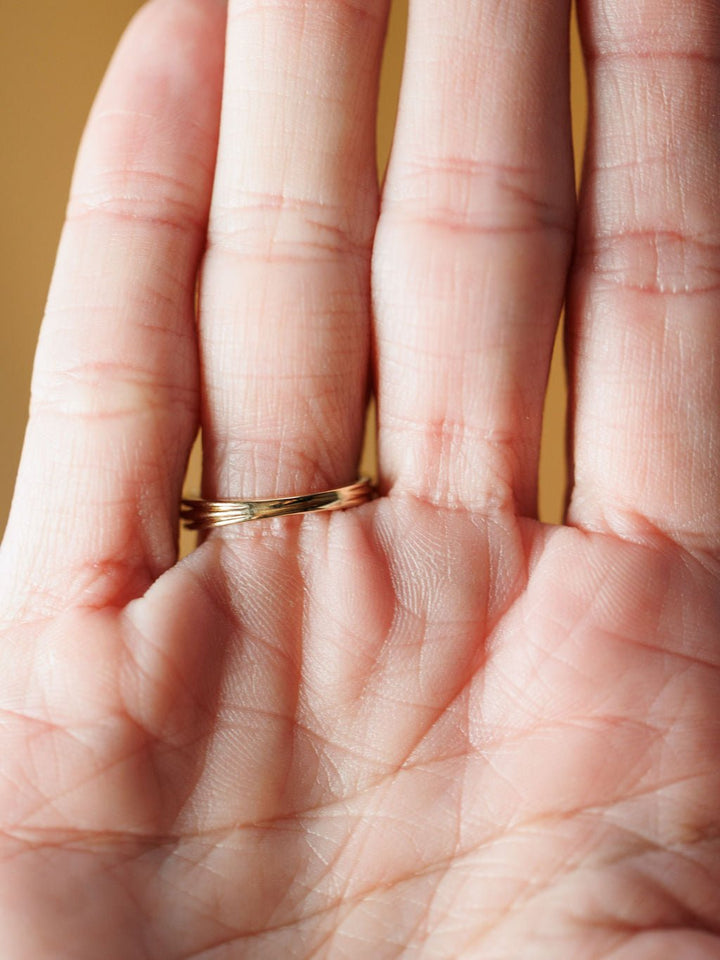 A close-up of an open hand with visible palm lines showcases the Diamond Milgrain Ring by Savannah Sevens western life{&}style on the ring finger against a warmly glowing, softly blurred background.