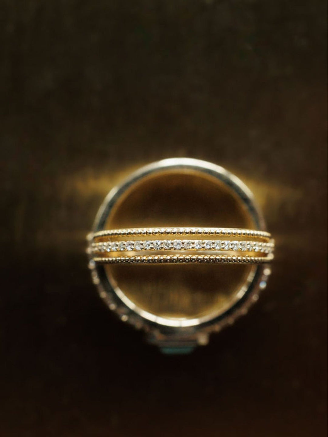 A close-up of two Savannah Sevens western life{&}style Diamond Milgrain Rings in 14K gold, stacked together. One ring features a row of small diamonds and delicate milgrain details, set against a dark, blurred background. Collaboration the Devereaux Gold.