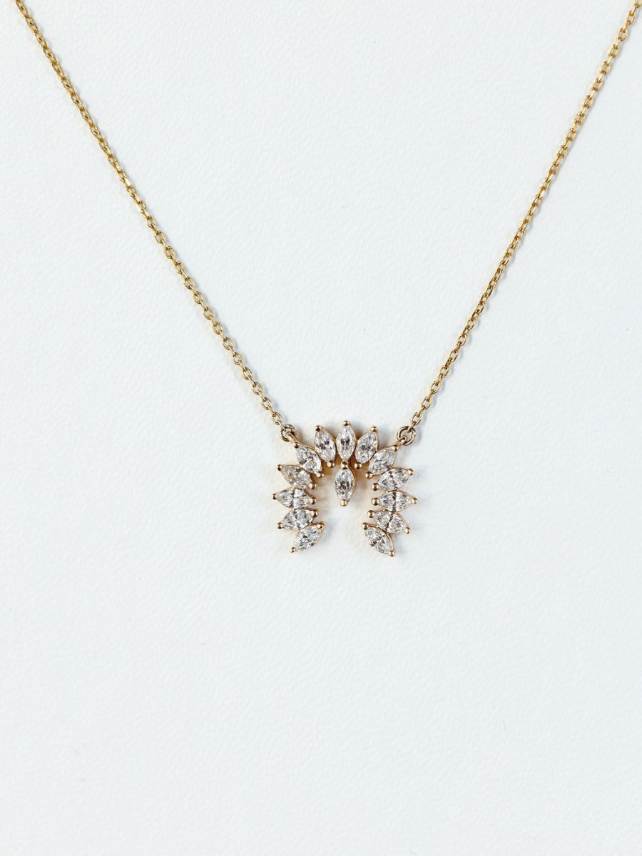 The Diamond Naja Necklace by Savannah Sevens western life{&}style features a gold chain with a symmetrical pendant of lab-grown marquise and round diamonds, arranged in a leafy pattern and shining elegantly on a plain white background.