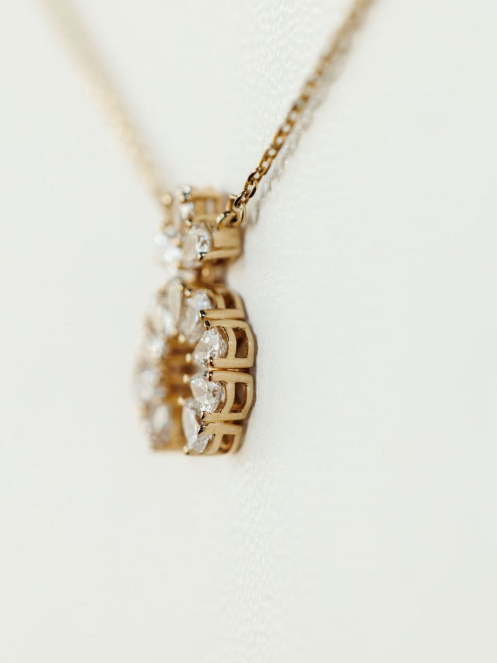 A close-up of the Diamond Squash Necklace by Savannah Sevens western life{&}style, featuring an intricate 14K gold pendant adorned with multiple sparkling lab grown diamonds against a soft, light background.