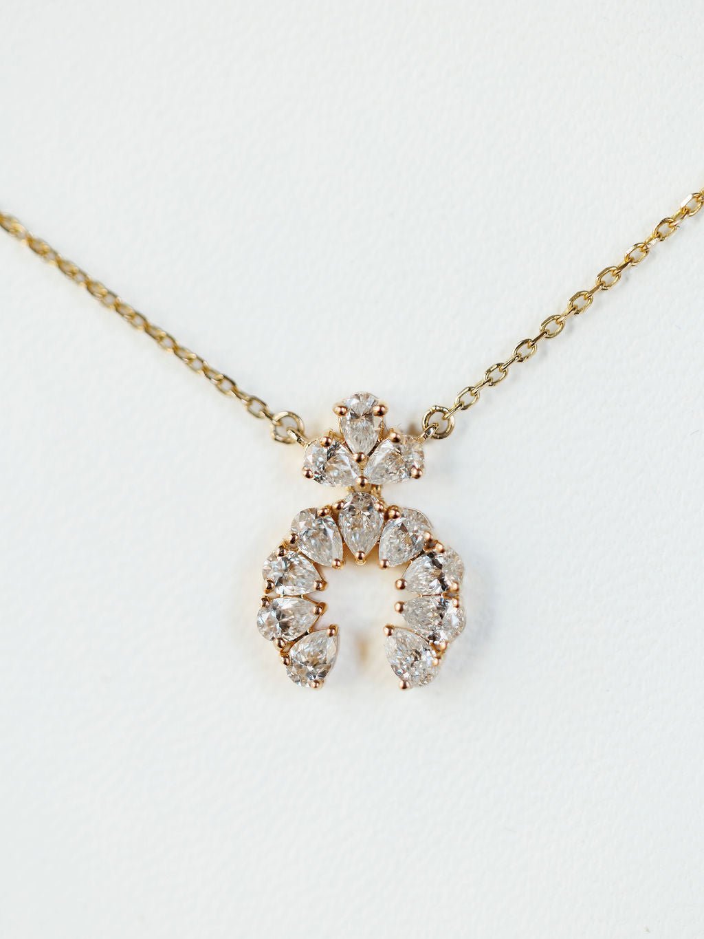 The Diamond Squash Necklace by Savannah Sevens western life{&}style features a 14K gold chain with clear, pear-shaped diamonds in horseshoe and triangular designs, shown against a white background.
