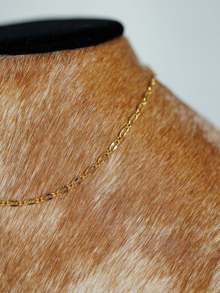 The Eckley Necklace by Savannah Sevens western life{&}style is an 18K gold filled paperclip chain, shown on a brown and white fur-covered mannequin dressed in a black top.