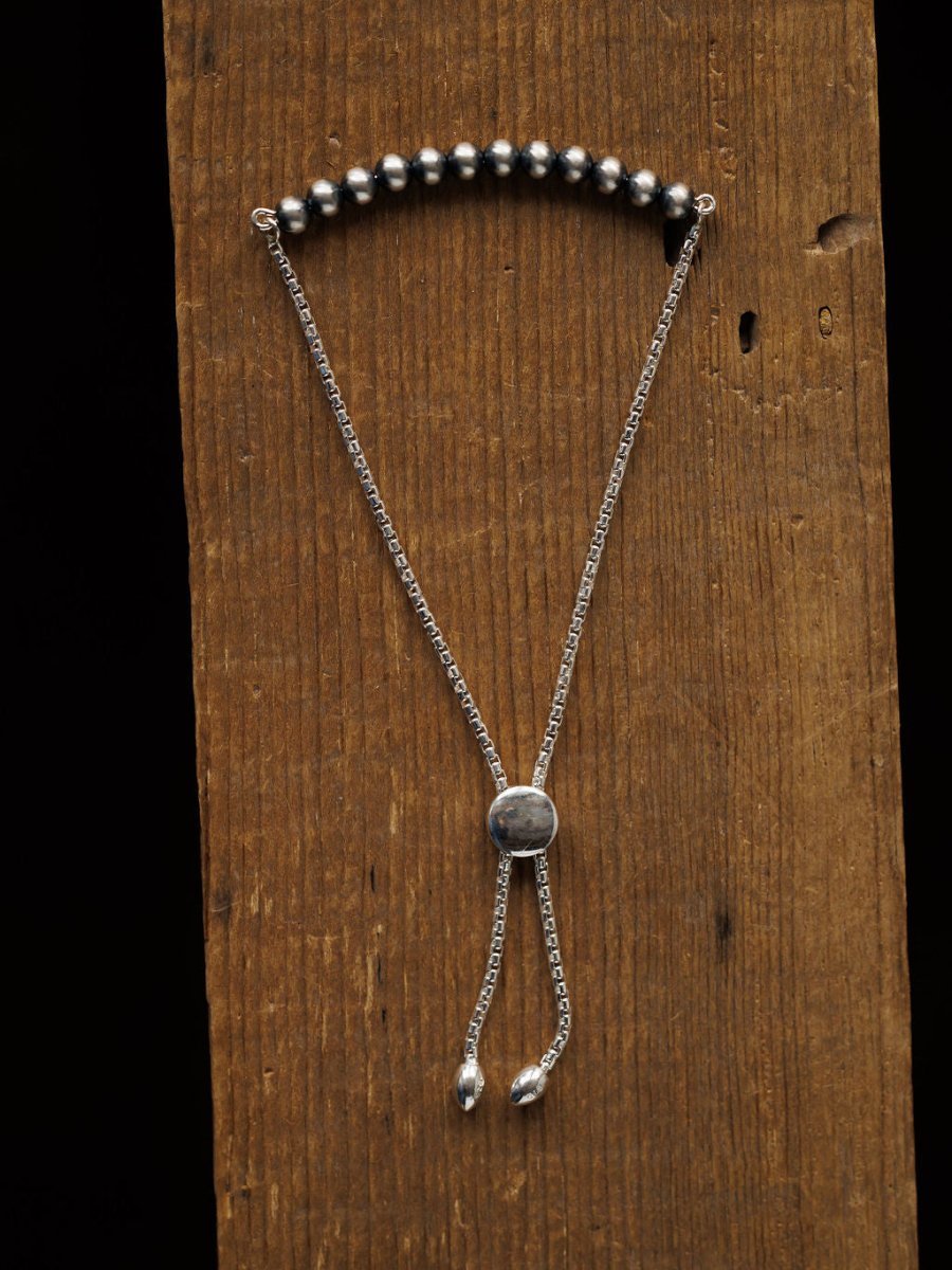 The Elida Bracelet by Savannah Sevens western life{&}style is a sterling silver beaded adjustable bracelet with a sliding clasp, shown vertically on rustic wood. This elegant piece adds timeless style to any look.
