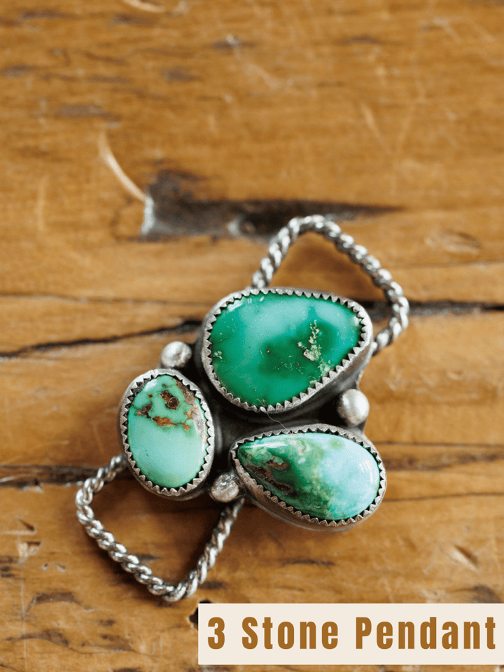 The Etowah Scarf Pendant by Savannah Sevens western life{&}style features three green and Kingman turquoise stones set in sterling silver bezels, shown on a wooden surface. Text at the bottom reads 3 Stone Pendant.