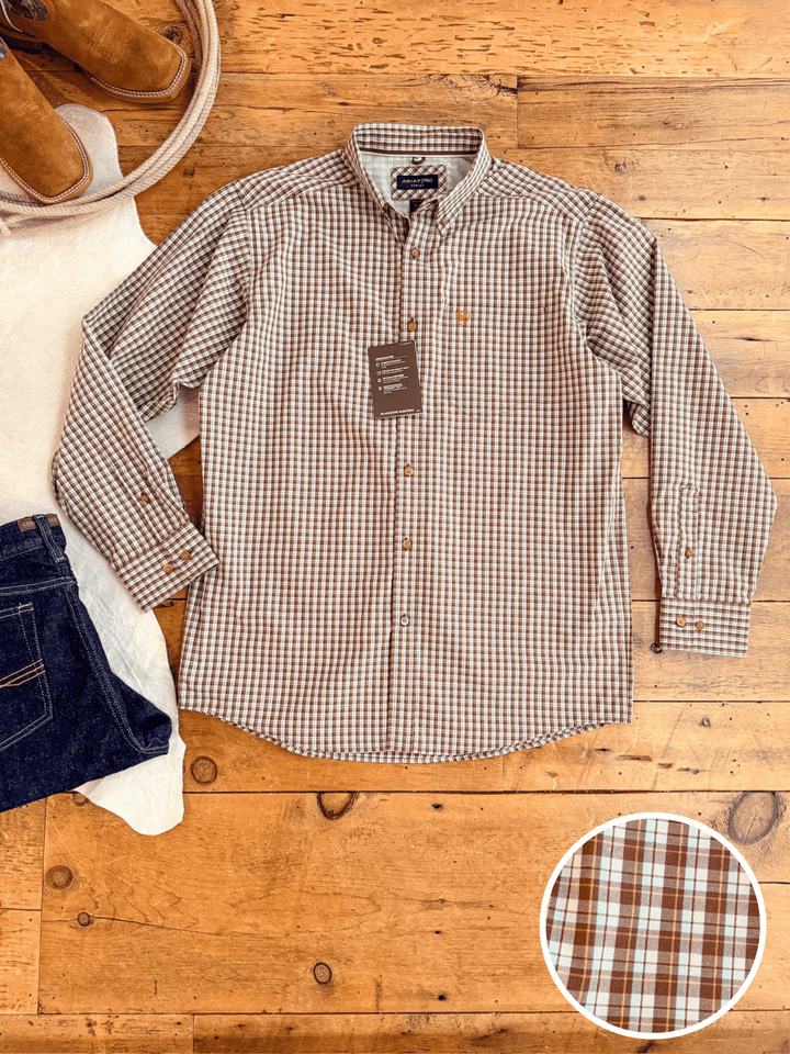 The Everett Ariat Men's Chocolate Plaid Button Up by Savannah Sevens western life{&}style is laid flat with jeans, tan shoes, and a cream sweater. An inset shows its brown and white checked pattern and moisture-wicking fabric.