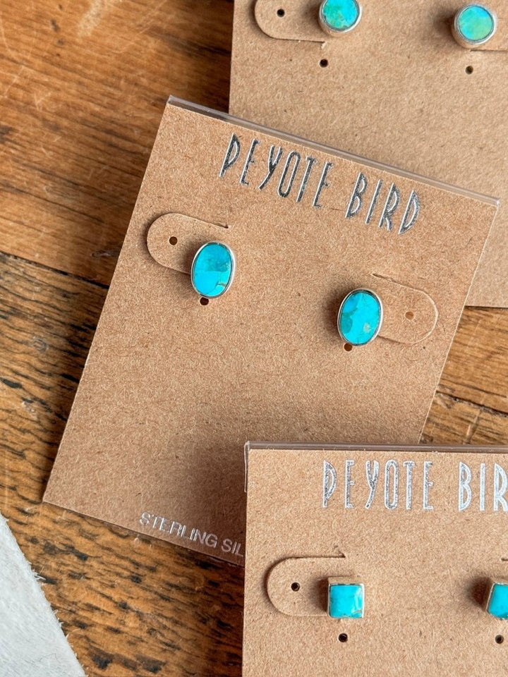 A pair of Falcon Earrings by Savannah Sevens western life{&}style is shown on a brown card labeled “sterling silver,” resting on a wooden surface.