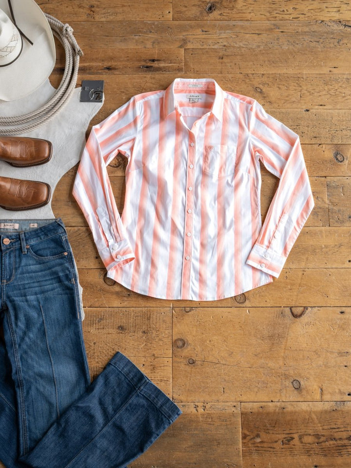 The Forada by Savannah Sevens western life{&}style, a pink and white striped stretch button-up top, is styled on a wooden floor with blue jeans, brown boots, a white cowboy hat, and a coiled rope.