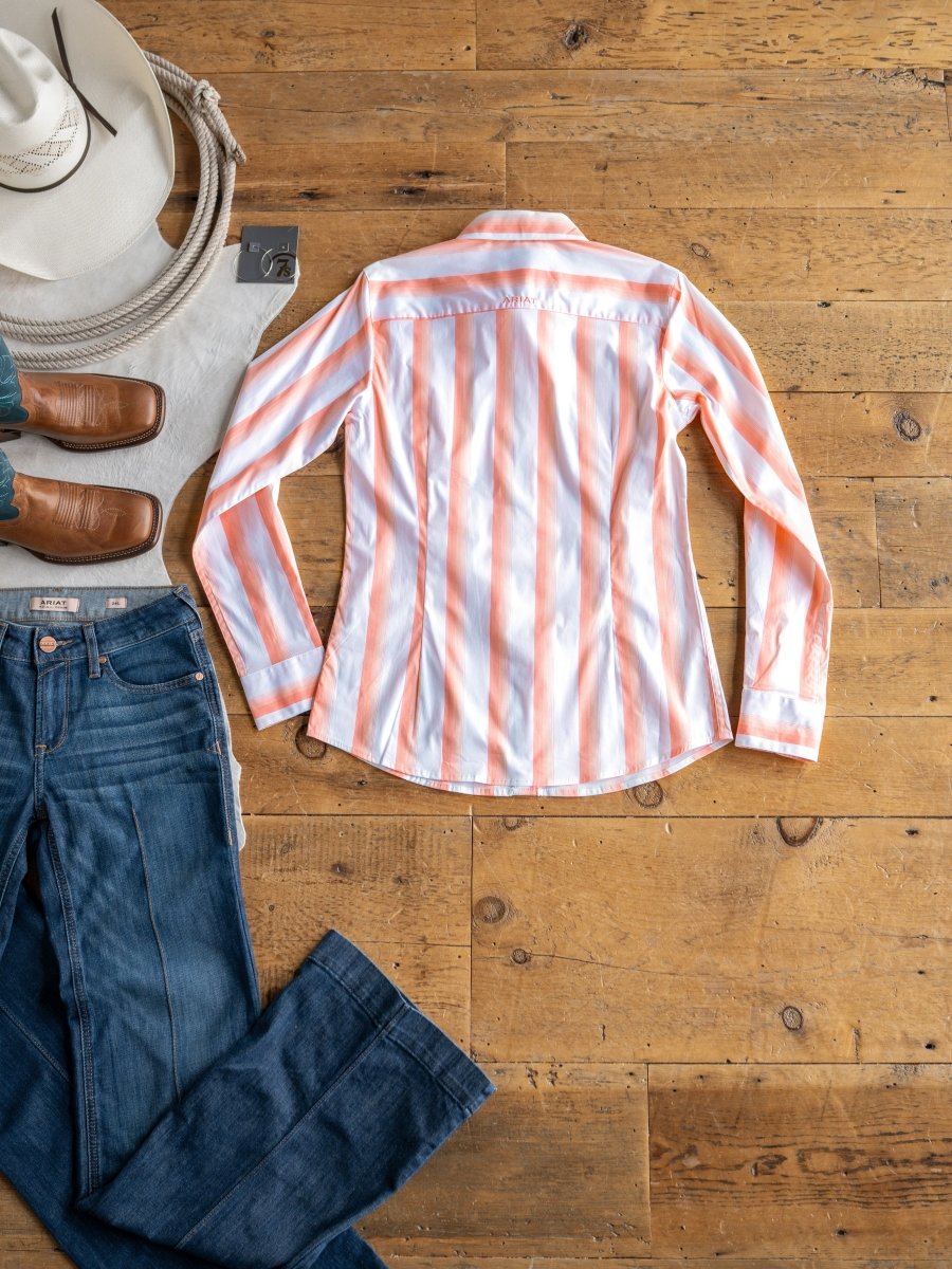 The Forada by Savannah Sevens western life{&}style is a pink and white striped, long-sleeve, wrinkle-resistant button-up shirt. Styled flat with blue jeans, brown cowboy boots, and a white cowboy hat for classic Western flair.