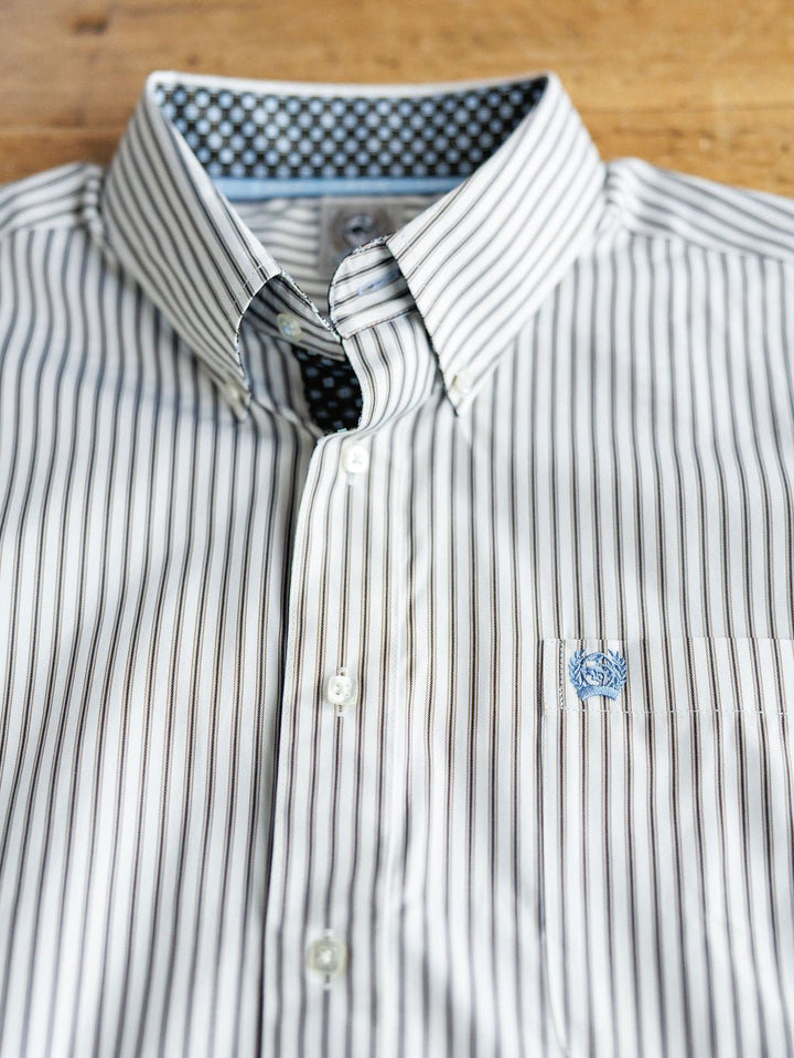 The Fordland men's shirt by Savannah Sevens western life&style features thin black stripes, a patterned inner collar, and an embroidered logo on the pocket, neatly displayed on a wooden surface.
