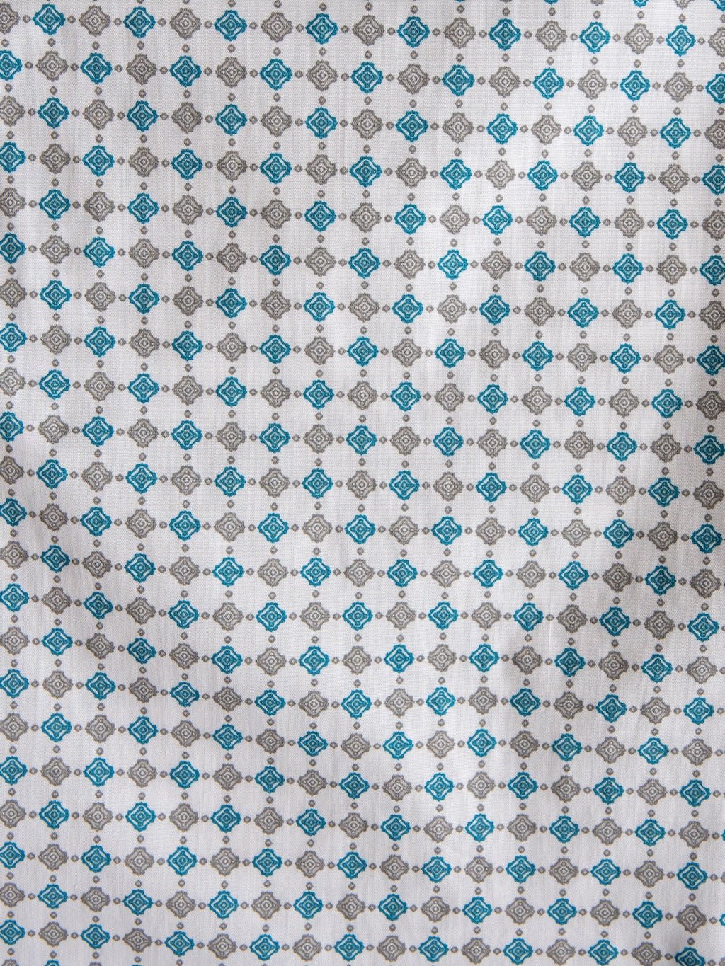 White fabric featuring a repeating geometric pattern of small blue and gray diamond shapes, arranged in evenly spaced rows and columns—ideal for the Georgetown Wrangler Men's Southwest Button Up by Savannah Sevens western life{&}style.