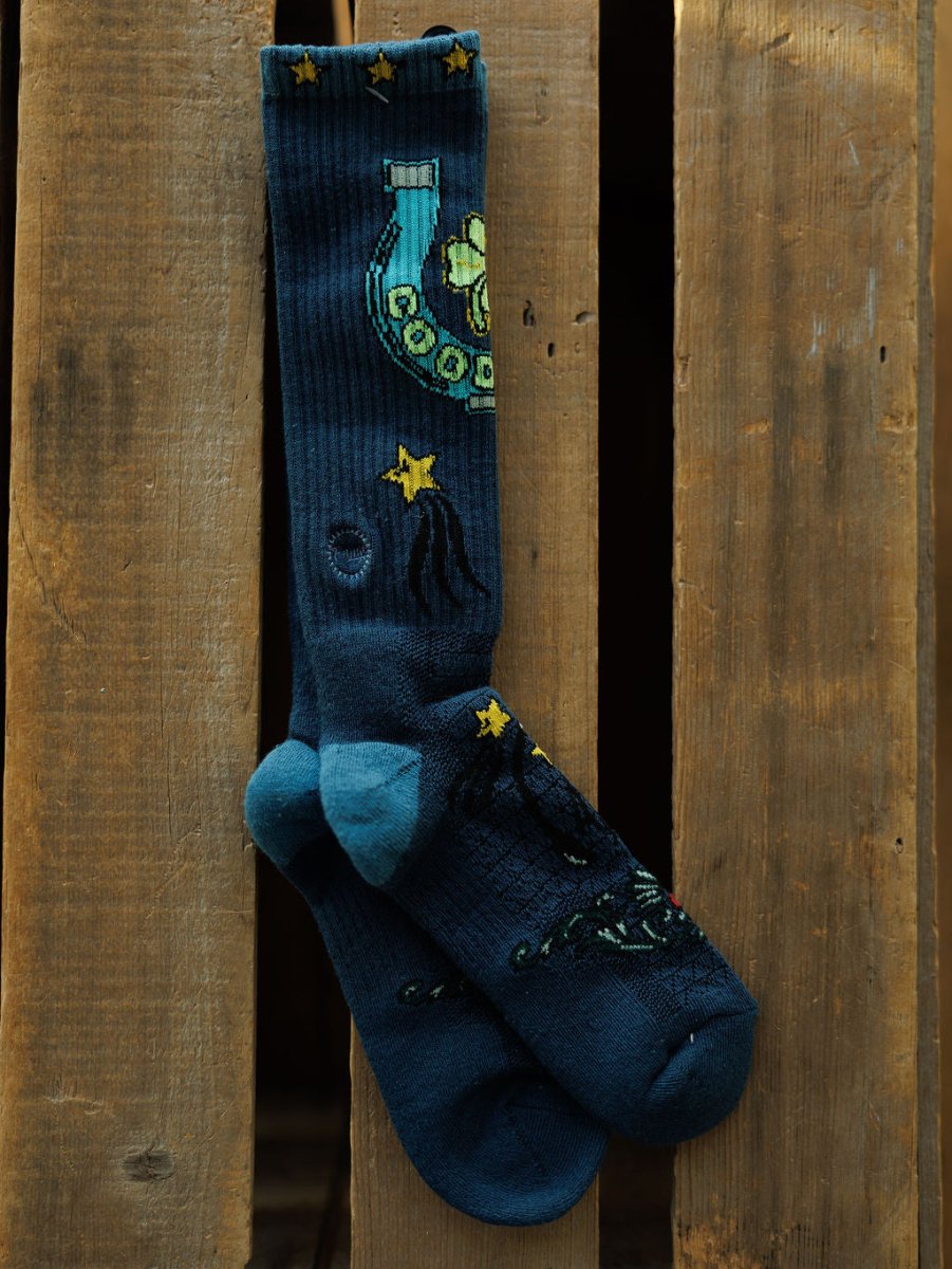 Good Luck Crew Socks by Savannah Sevens western life{&}style: dark blue western crew socks with light blue toes and heels, decorated with stars, a yellow rotary phone, and celestial designs, displayed against a wooden background.