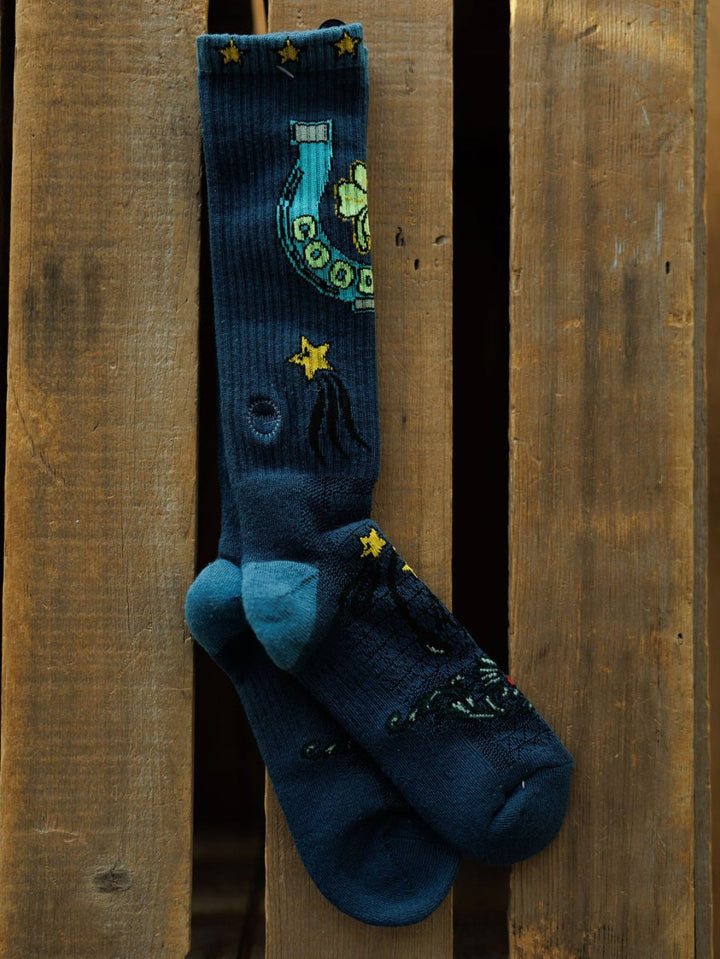 Good Luck Crew Socks by Savannah Sevens western life{&}style: dark blue western crew socks with light blue toes and heels, decorated with stars, a yellow rotary phone, and celestial designs, displayed against a wooden background.