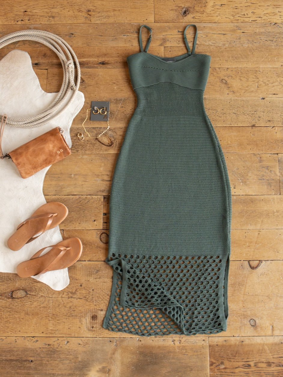 A Granada Blue Sage Crochet Dress by Savannah Sevens western life{&}style is laid out with tan sandals, a suede purse, jewelry, a cowhide rug, and rope on a wooden floor.