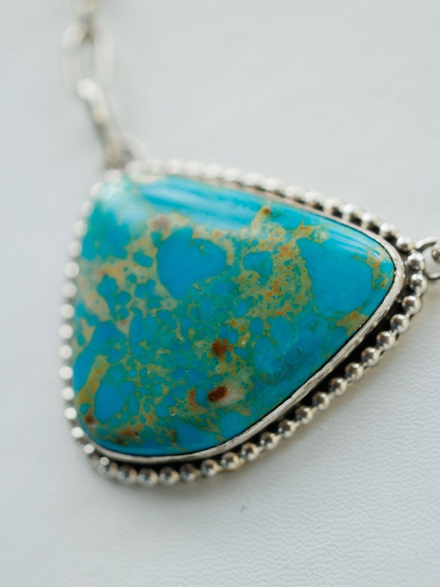Close-up photo of the Granada Necklace by Savannah Sevens western life{&}style, featuring Kingman turquoise with brown and green patterns, set in a sterling silver beaded frame on a chain, displayed on a light background.