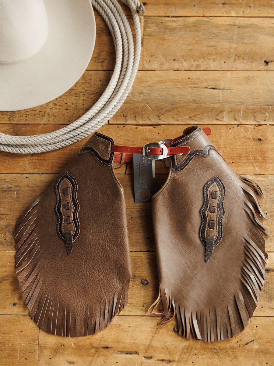 The Granger Chinks {Youth} by Savannah Sevens western life{&}style, a red belt, white cowboy hat, and coiled rope are arranged on a wooden surface.