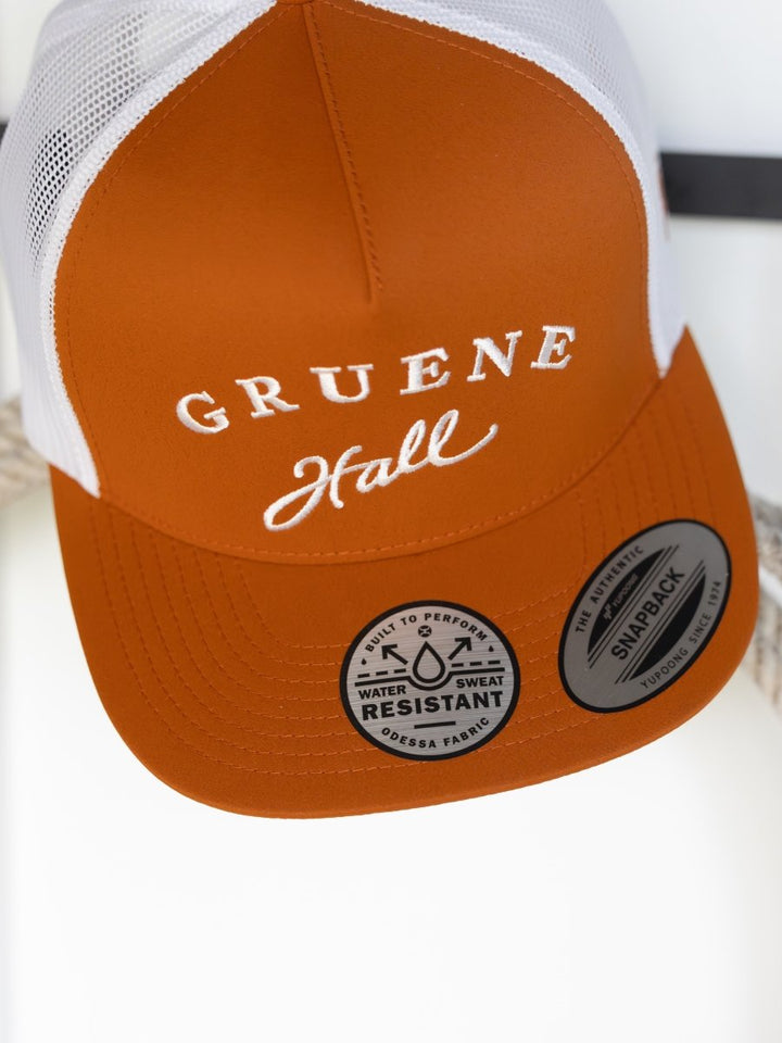 The Gruene Hall Cap by Savannah Sevens western life{&}style is an orange and white trucker cap with Hooey embroidery, Water & Sweat Resistant labels, and a Snapback closure.