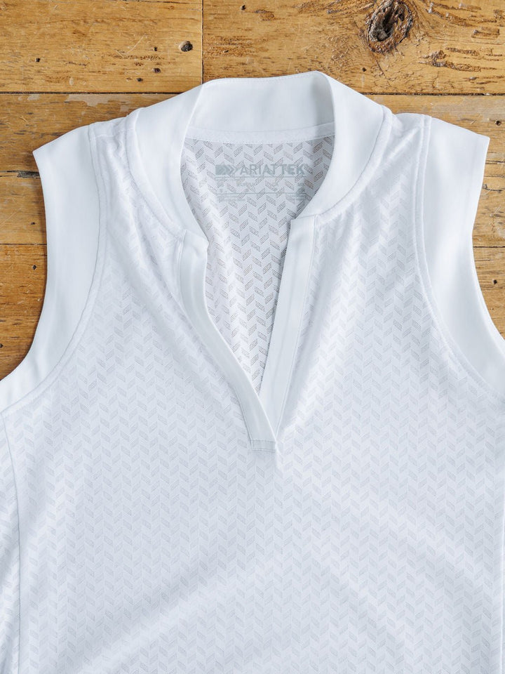 The Hanover Ariat White Golf Tank by Savannah Sevens western life{&}style, featuring a subtle chevron pattern, partial zip-up collar, and breathable mesh fabric, is laid flat on a wooden surface.