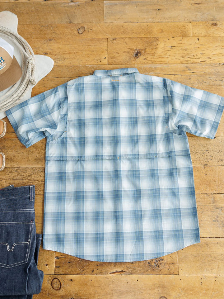 The Harrison Ariat Men's Blue Plaid Button Up by Savannah Sevens western life{&}style features moisture-wicking fabric. Laid flat next to blue jeans, a straw hat, and brown sandals, this plaid short sleeve shirt offers comfort and style.
