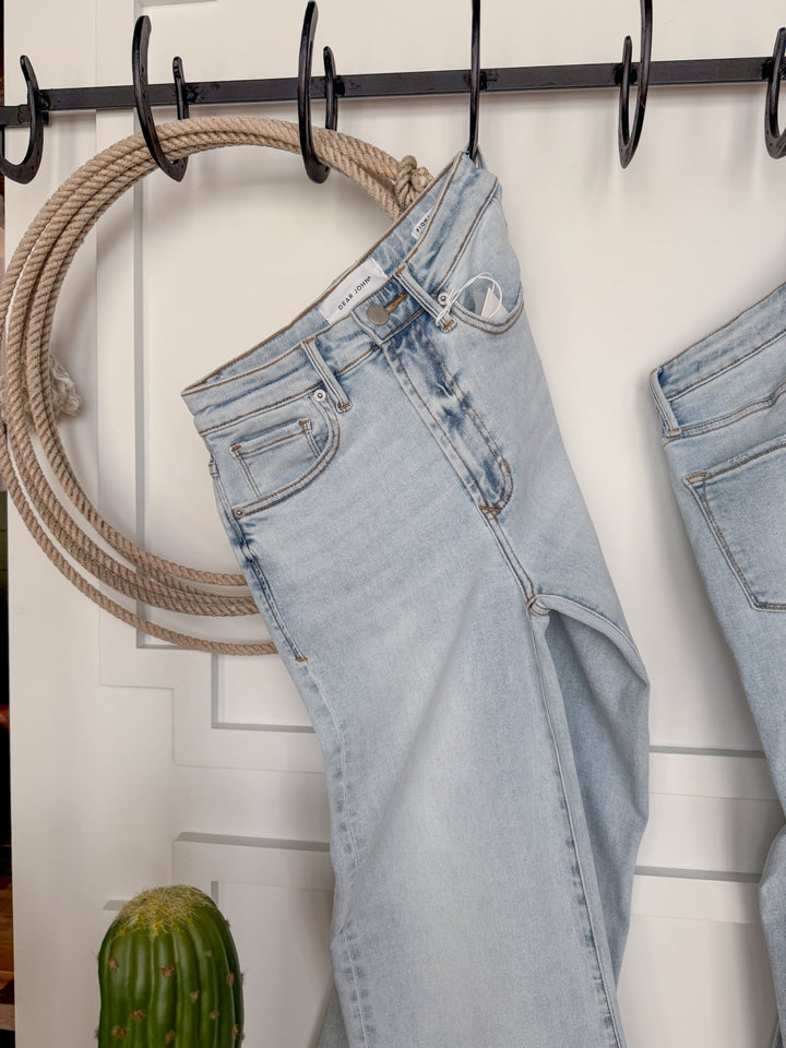 The Hayes High Rise Wide Leg Jean by Savannah Sevens western life{&}style hangs on a black hook, with a coiled rope on the wall behind and a small cactus at the bottom left of the image.