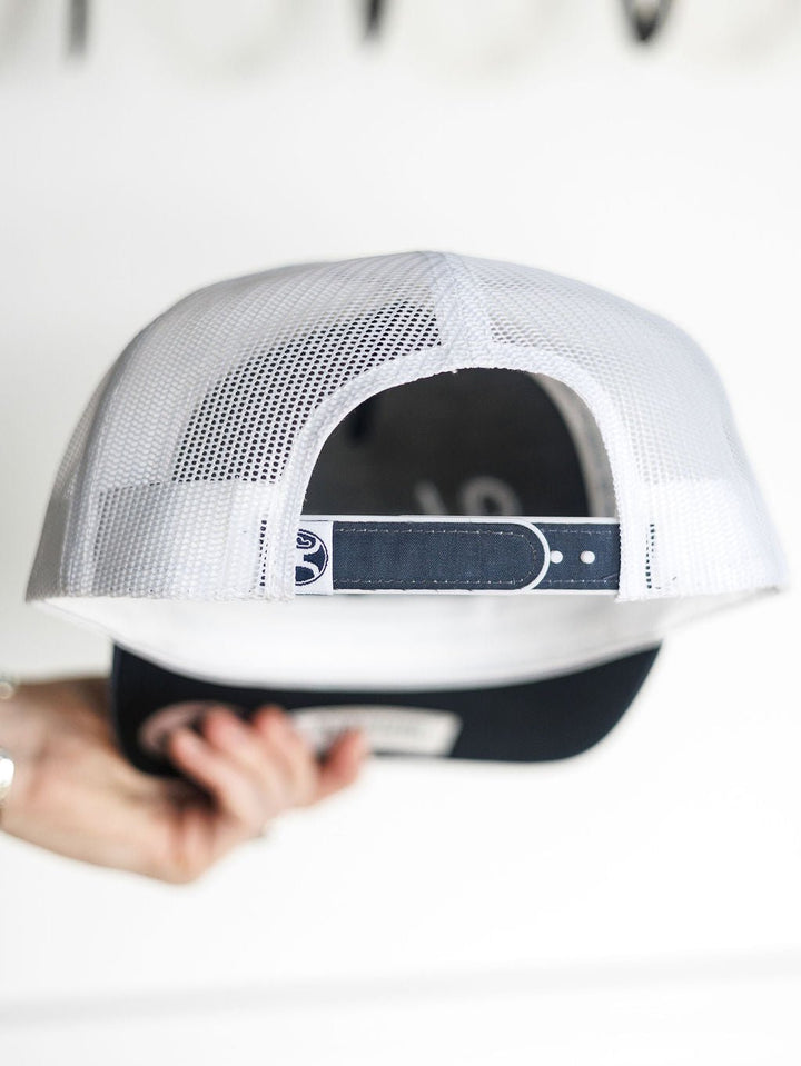 A hand holds the Hooey Colby Cap by Savannah Sevens western life{&}style, displaying its white mesh and adjustable snap back strap from the rear view.