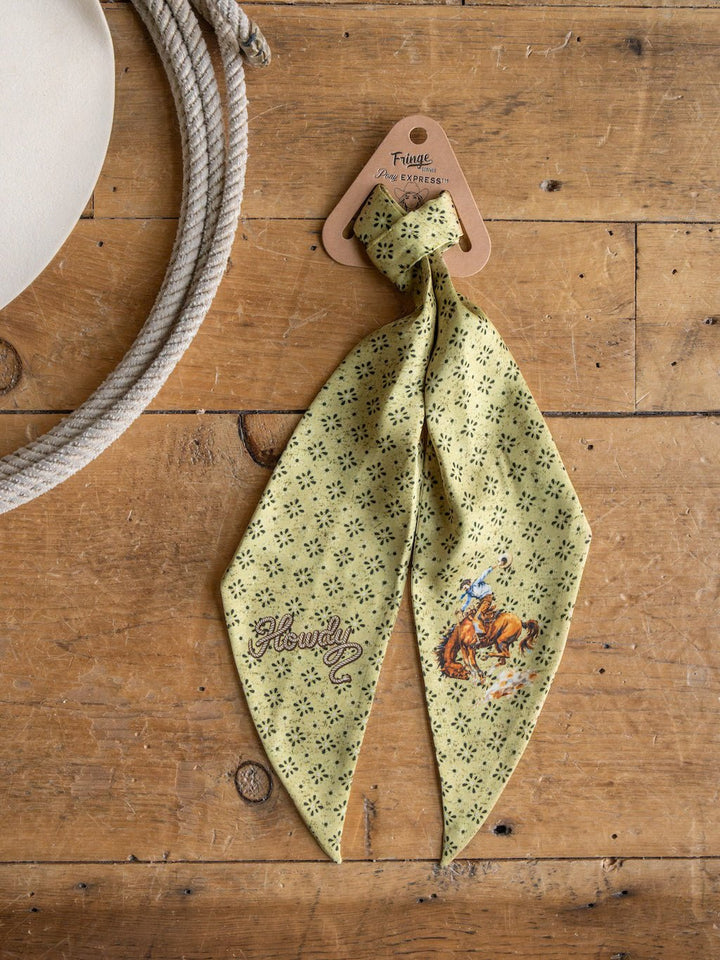 Introducing the Howdy Chartreuse Satin Tie Scarf by Savannah Sevens western life{&}style—a vibrant green neckerchief featuring black dotted patterns, playful Howdy! text, and a cowboy on horseback illustration. Made from satin poly chiffon, this stylish western scarf is showcased on a wooden surface next to a white hat, offering a fun accent to any ensemble.