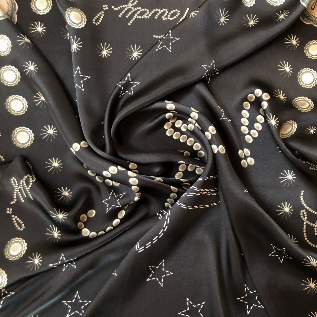 The Howdy Wild Rag {Noir} by Savannah Sevens western life{&}style is a black silk scarf with white and gold star, dot, and celestial patterns—perfect as a bold cosmic-inspired western accessory.
