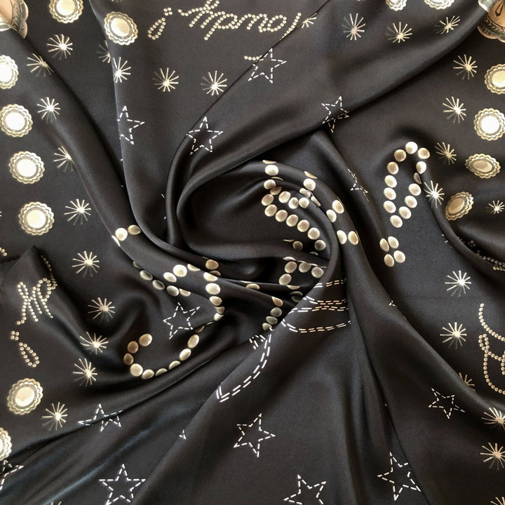 The Howdy Wild Rag {Noir} by Savannah Sevens western life{&}style is a black silk scarf with white and gold star, dot, and celestial patterns—perfect as a bold cosmic-inspired western accessory.