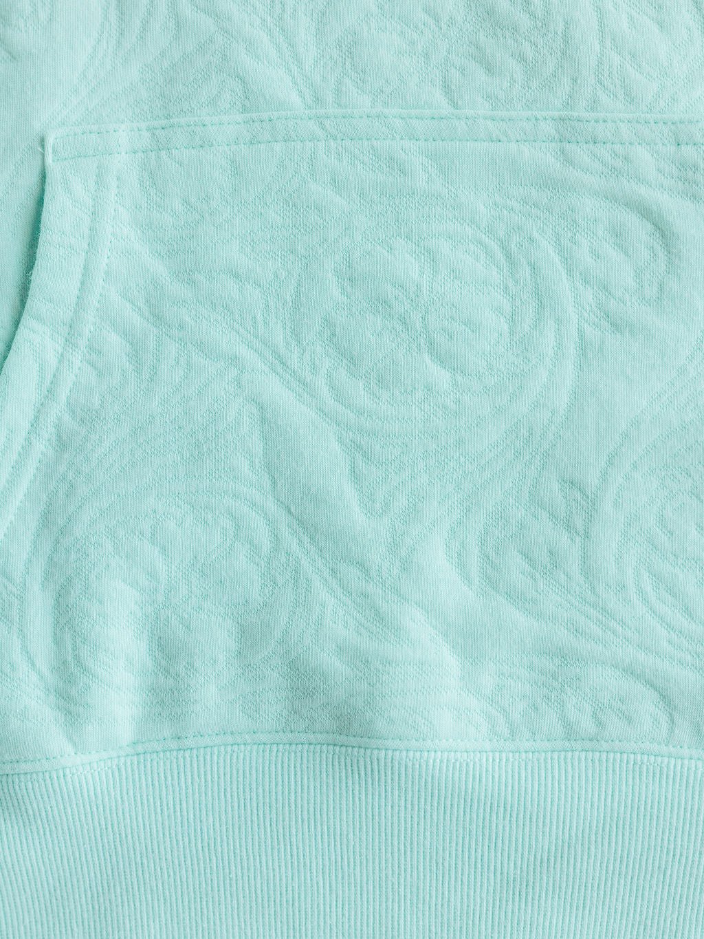 Close-up of The Hoyt hoodie by Savannah Sevens western life{&}style (S-XXL) in light turquoise cotton blend, featuring a subtle raised floral & swirl pattern, ribbed hem, and highlighted pocket for stylish comfort.