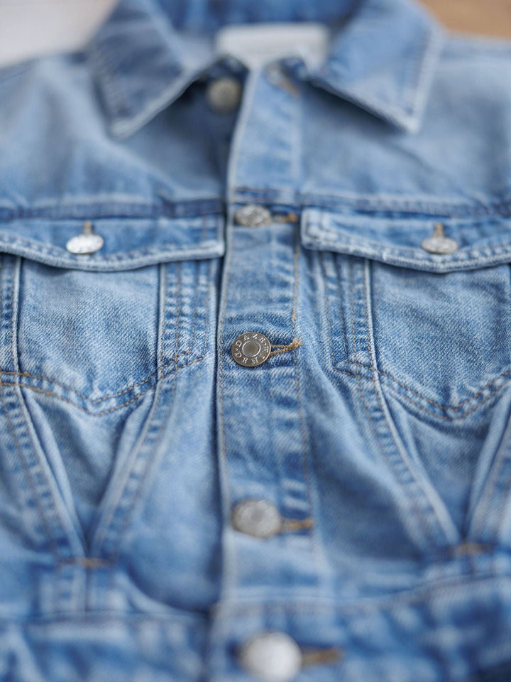Close-up of the front of the Humboldt Denim Button Dress by Savannah Sevens western life{&}style, showing western-style blue denim with metal buttons, detailed stitching, and two flap chest pockets.