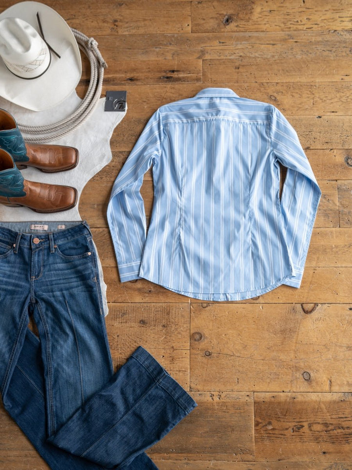 The Ingall by Savannah Sevens western life{&}style, a light blue striped button-up (S-XXL), is displayed with jeans, cowboy boots, a white hat, rope, and vest to showcase its wrinkle-resistant Western style.