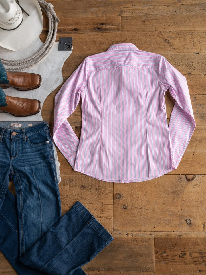 The Kinnear by Savannah Sevens western life{&}style, a wrinkle-resistant pink and white striped long sleeve top, is styled flat with blue jeans, brown cowboy boots, a white cowboy hat, and a coiled rope on a wooden floor.