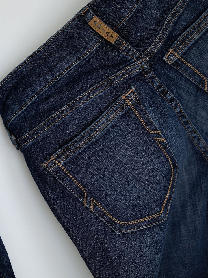 Close-up of the back pocket and waistband of Ariat’s The Kolt Perfect Rise Trouser Jean in medium dark wash, with brown stitching and a small brown label on the waistband for a flattering rise fit.