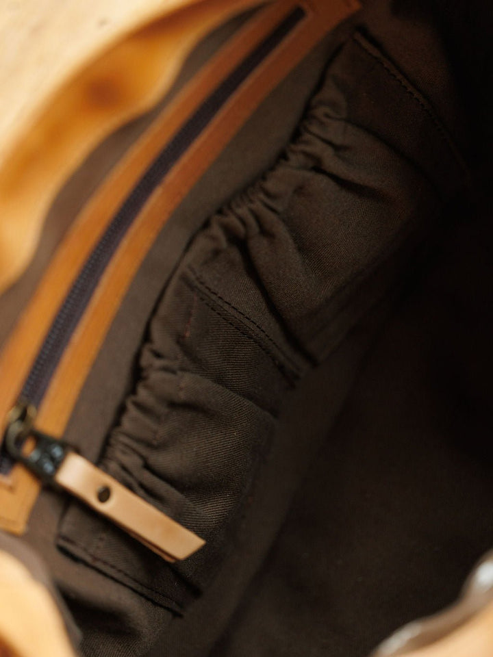 Close-up of the LaGrange Leather Saddle Bag Crossbody by Savannah Sevens western life{&}style, showing its brown fabric lining with elastic pockets and a zippered pocket with a leather pull tab.