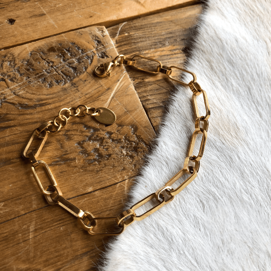 The Larkin Bracelet by Savannah Sevens western life{&}style features 18K gold filled rectangular links. Hypoallergenic and ideal for sensitive skin, it's pictured on a wooden surface beside white fur.