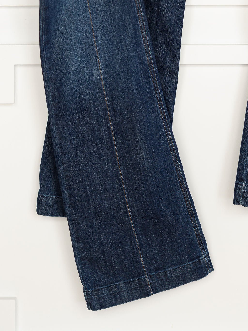 A close-up of the lower legs of The Ledger Perfect Rise Trouser Jean *Exclusive* in a medium dark wash, hanging against a white background.