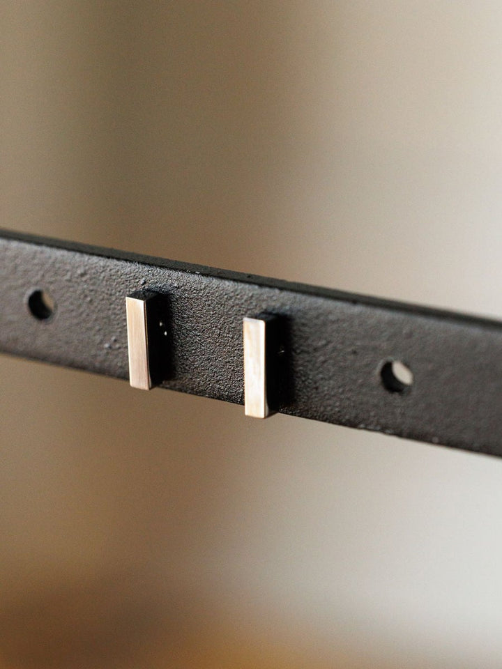 Close-up of the Lexington Earrings by Savannah Sevens western life{&}style—black metal bar studs featuring two rectangular silver pegs and three round holes, set against a blurred neutral background.