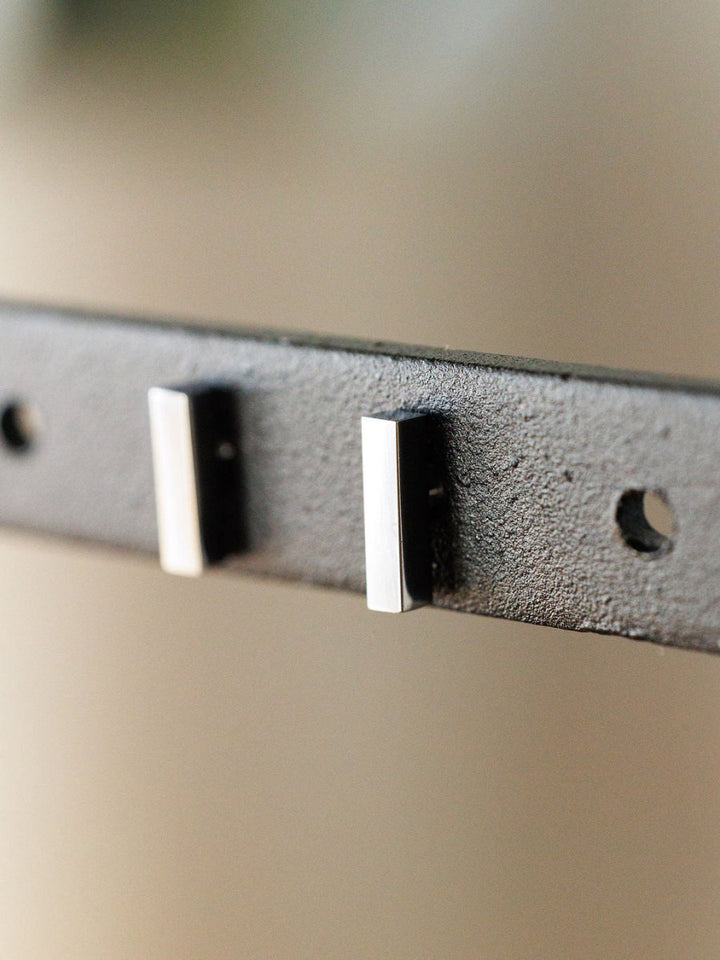 Close-up of the Lexington Earrings by Savannah Sevens western life{&}style—two rectangular silver bar studs on a black metal bracket with two empty circular holes, viewed at an angle against a blurred background.