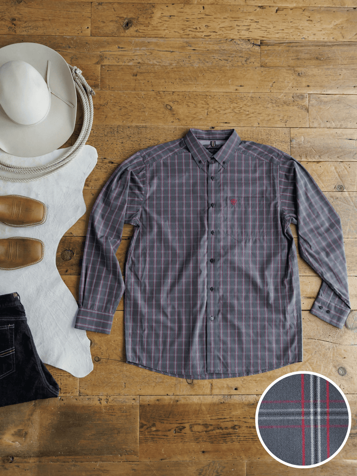 The Livingston Ariat Men's Grey Plaid Button Up from Savannah Sevens western life{&}style is laid flat on a wooden floor with a white cowboy hat, leather boots, dark jeans, and rope nearby. An inset highlights the red and white plaid pattern.