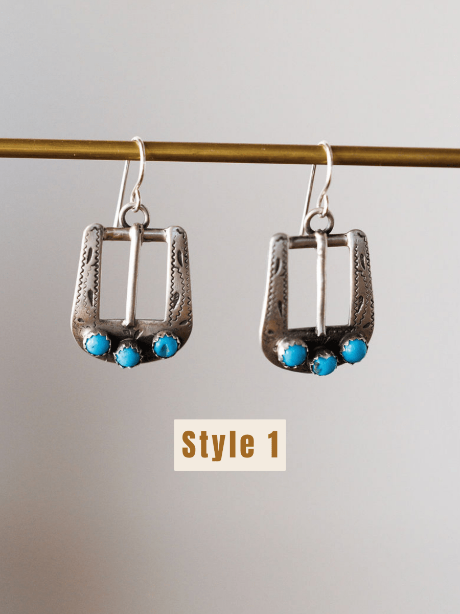 The Los Alamos Earrings by Savannah Sevens western life{&}style feature a rectangular sterling silver frame with ornate details and three small turquoise stones at the bottom. "Style 1" is shown below these turquoise earrings hanging on a rod.