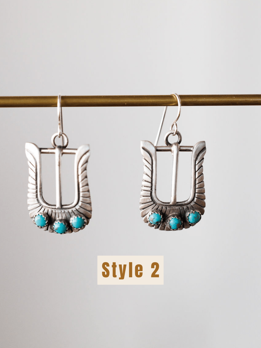The Los Alamos Earrings by Savannah Sevens western life{&}style are sterling silver buckle-shaped earrings with three turquoise stones at the base, suspended from a horizontal rod. “Style 2” is shown below these unique turquoise earrings.