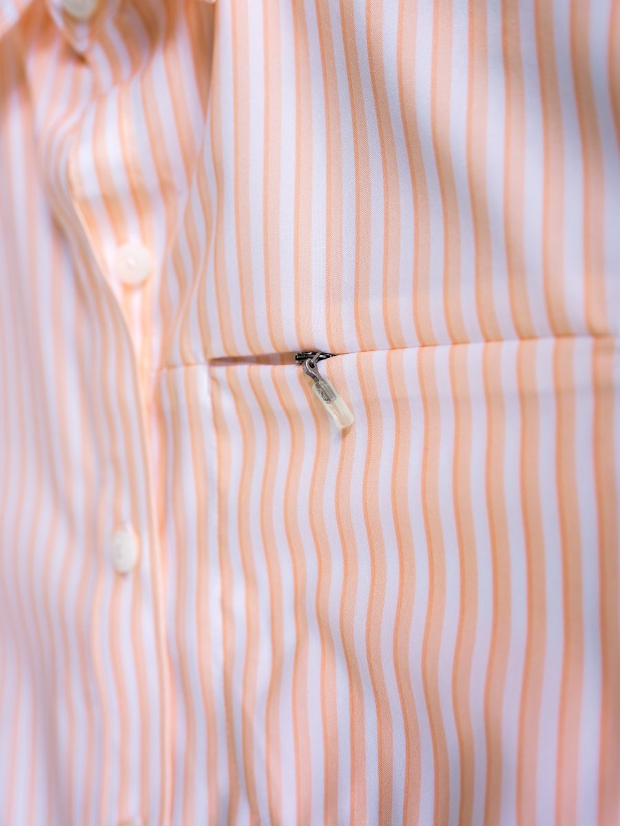 Close-up of The Lovilia shirt by Savannah Sevens western life{&}style with vertical peach and white stripes, white buttons, and a chest zippered pocket. This sun protection top offers moisture wicking comfort for all-day wear.