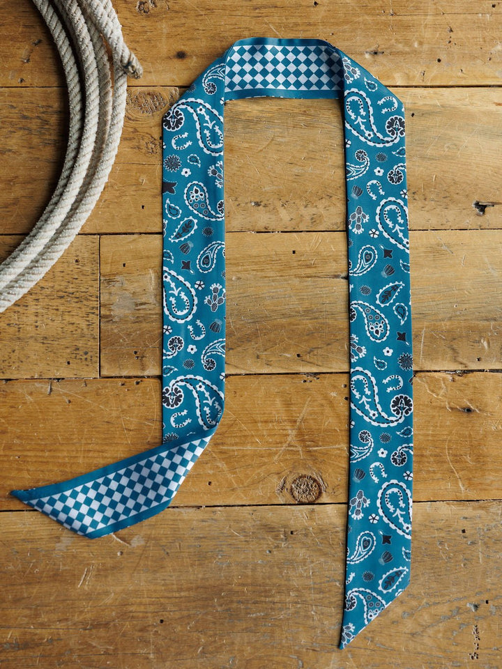 The Lucky Paisley Twilly {Cool Blue} by Savannah Sevens western life{&}style is a blue paisley scarf with checkered ends, shown flat beside a coiled rope—ideal as a head wrap or satin tie scarf.
