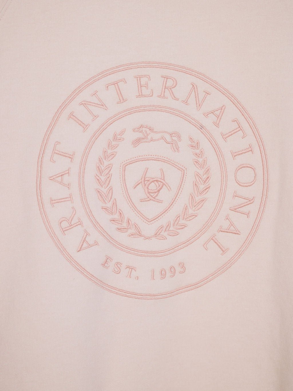 The Lynwood Ariat Light Pink Pullover by Savannah Sevens western life{&}style is crafted from organic cotton, fleece lined, and features a circular embossed ARIAT INTERNATIONAL EST. 1993 emblem with a horse, laurel wreath, shield, horseshoe & horses’ heads.