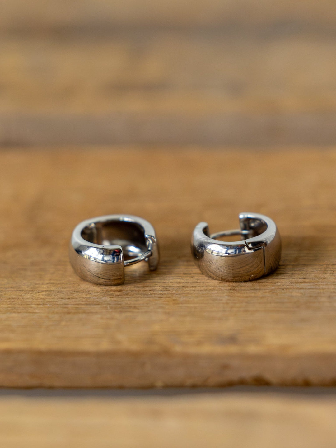 The Savannah Sevens western life{&}style Madera Gold/Silver Mini Hoop Earrings, shown slightly open and side by side on wood, offer a timeless accent for any look.