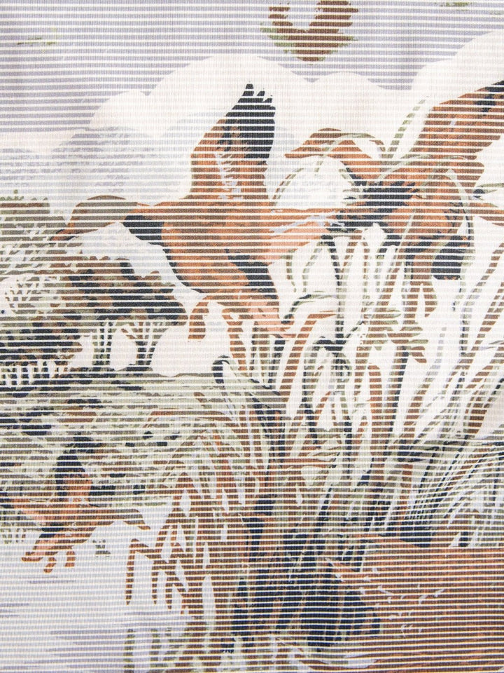 A striped, stylized illustration of ducks taking flight over tall grass by the water, with abstract trees and clouds in the background in earthy shades of brown, beige, and gray reflects both the moisture-wicking comfort and UV protection you’ll find in the Savannah Sevens western life{&}style Mallard Cinch Men's Graphic Polo.