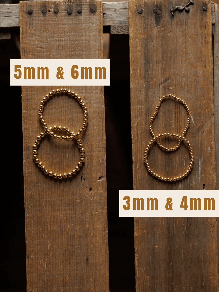 Two sets of Mancos Bracelet {Set} by Savannah Sevens western life{&}style are shown on wooden planks. The left set (5mm & 6mm) has larger beads, while the right set (3mm & 4mm) features smaller gold-plated beads.