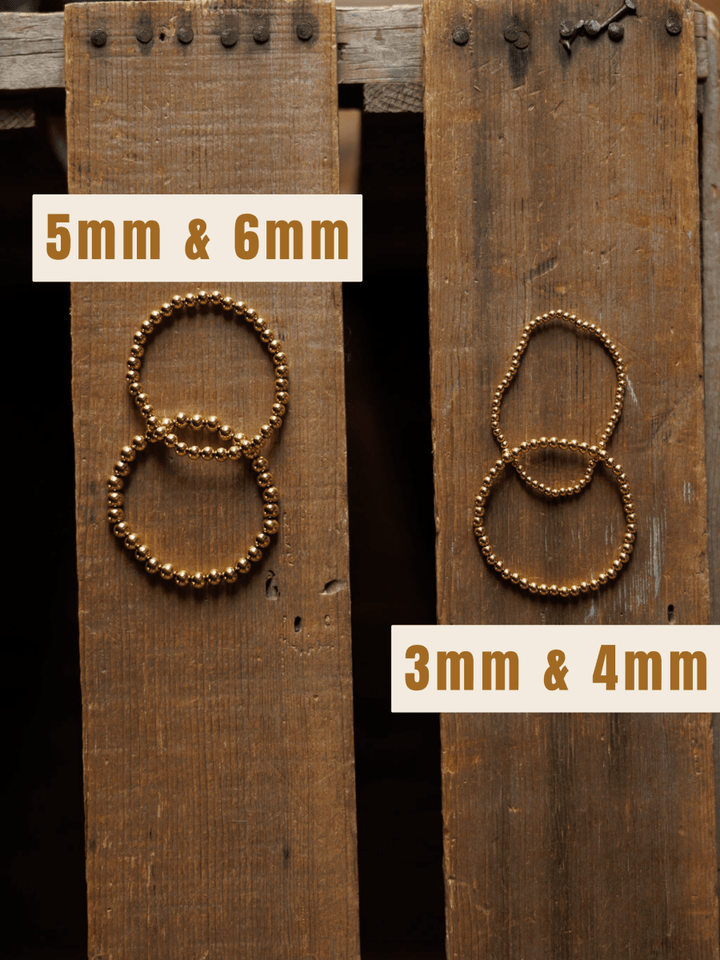 Two sets of Mancos Bracelet {Set} by Savannah Sevens western life{&}style are shown on wooden planks. The left set (5mm & 6mm) has larger beads, while the right set (3mm & 4mm) features smaller gold-plated beads.
