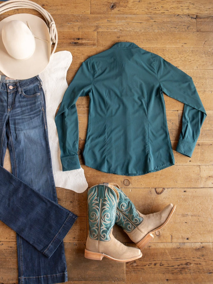 Western outfit flat lay featuring a white cowboy hat, blue jeans, the Savannah Sevens western life{&}style Mankato Teal Mesh Performance Shirt with UV defense, tan and teal cowboy boots, and a white hide on a wooden floor.