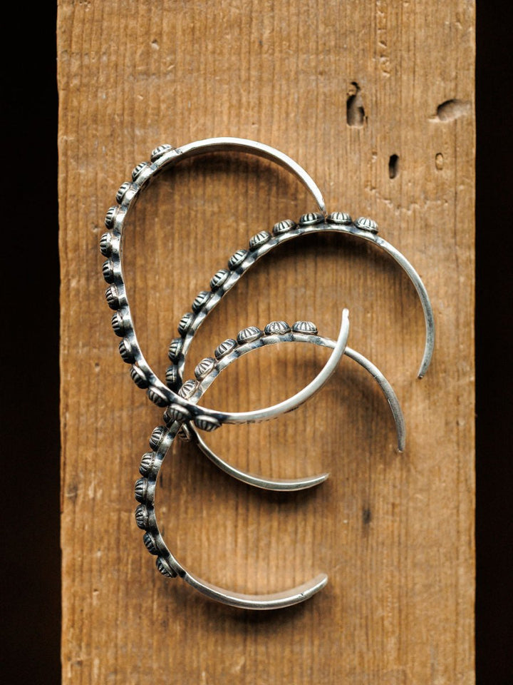 Three Marimar Cuffs by Savannah Sevens western life{&}style, featuring decorative beading inspired by southwest jewelry, are arranged in a spiral pattern on a vertical wooden surface and viewed from above.