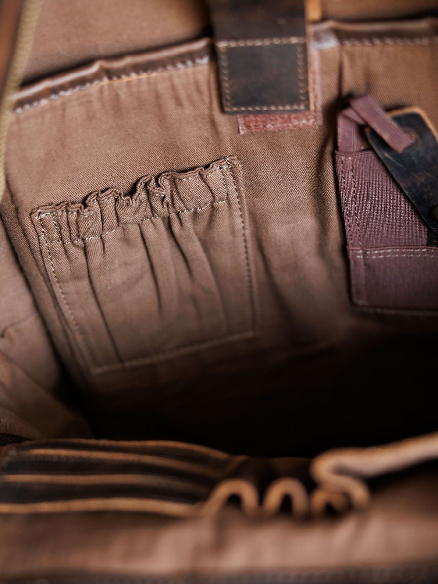 Close-up of the Mohave Backpack by Savannah Sevens western life{&}style, highlighting interior organized pockets such as an elastic pouch and a leather-trimmed section, designed to securely hold small items. By STS.